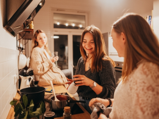 Drei junge Frauen in einer kleinen Küche kochen gemeinsam